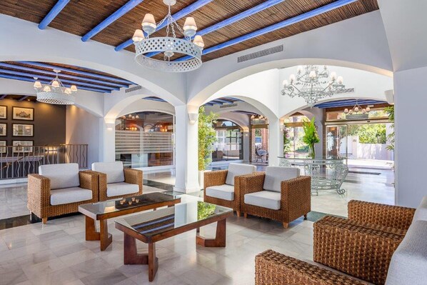 A spacious lobby with wicker furniture, a glass coffee table, and a chandelier. - Marbella Resort 9 Pool Whirlpool Sauna (Marbella)