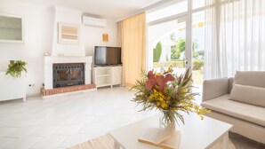 A modern living room with a fireplace, television, sofa, and a view of the outdoors. - Rancho Miraflores Townhouse 2 (Mijas)