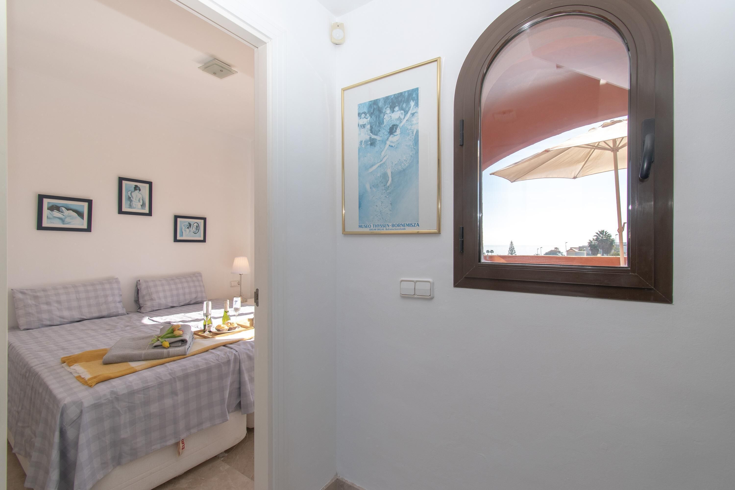 A bedroom with a bed, a bedside table with a lamp, and a framed picture on the wall.