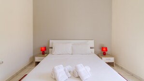 Hotellihuone, jossa on suuri sänky, kaksi yöpöytää ja kaksi punaista lamppua.