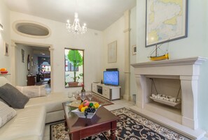 Ein Wohnzimmer mit einer Couch, einem Couchtisch mit Obst, einem Fernseher, einem Kamin und einer Karte an der Wand.