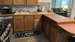 Una cocina con armarios de madera, un microondas, un lavabo y una estufa.