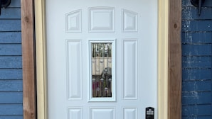 Una puerta blanca con una placa que indica el número '1408', una pequeña ventana y una cerradura electrónica.