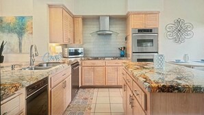 A kitchen with wooden cabinets, a stainless steel range hood, a microwave, and a built-in oven.