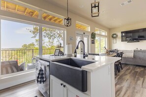 A modern kitchen with a large island, built-in cabinets, and a view of the outdoors.