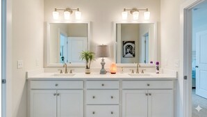 A bathroom with two sinks, a large mirror, and a potted plant.