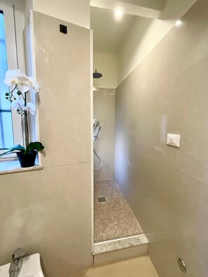 Familie appartement | Badkamer | Een douche, een haardroger, handdoeken, zeep
