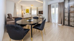 Un salon moderne avec une table de salle à manger ronde, des chaises noires, un canapé et un téléviseur.