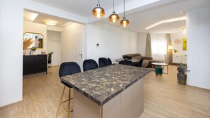Une cuisine moderne avec un îlot en marbre, des tabourets de bar noirs et des luminaires suspendus.