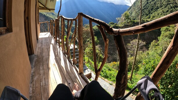 A wooden deck with a rustic railing overlooking a mountainous landscape. - Salkantay Hostel Chaullay (Santa Teresa)