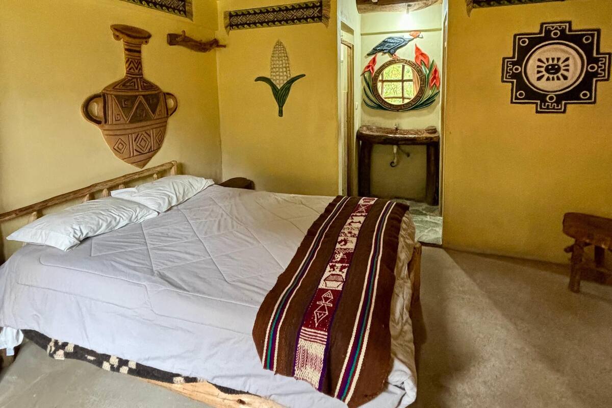 Una stanza con un letto di legno, un muro con decorazioni e un soffitto con travi a vista.