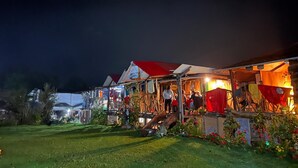A rustic outdoor market with wooden stalls and a red-roofed building. - Salkantay Hostel Chaullay (Santa Teresa)