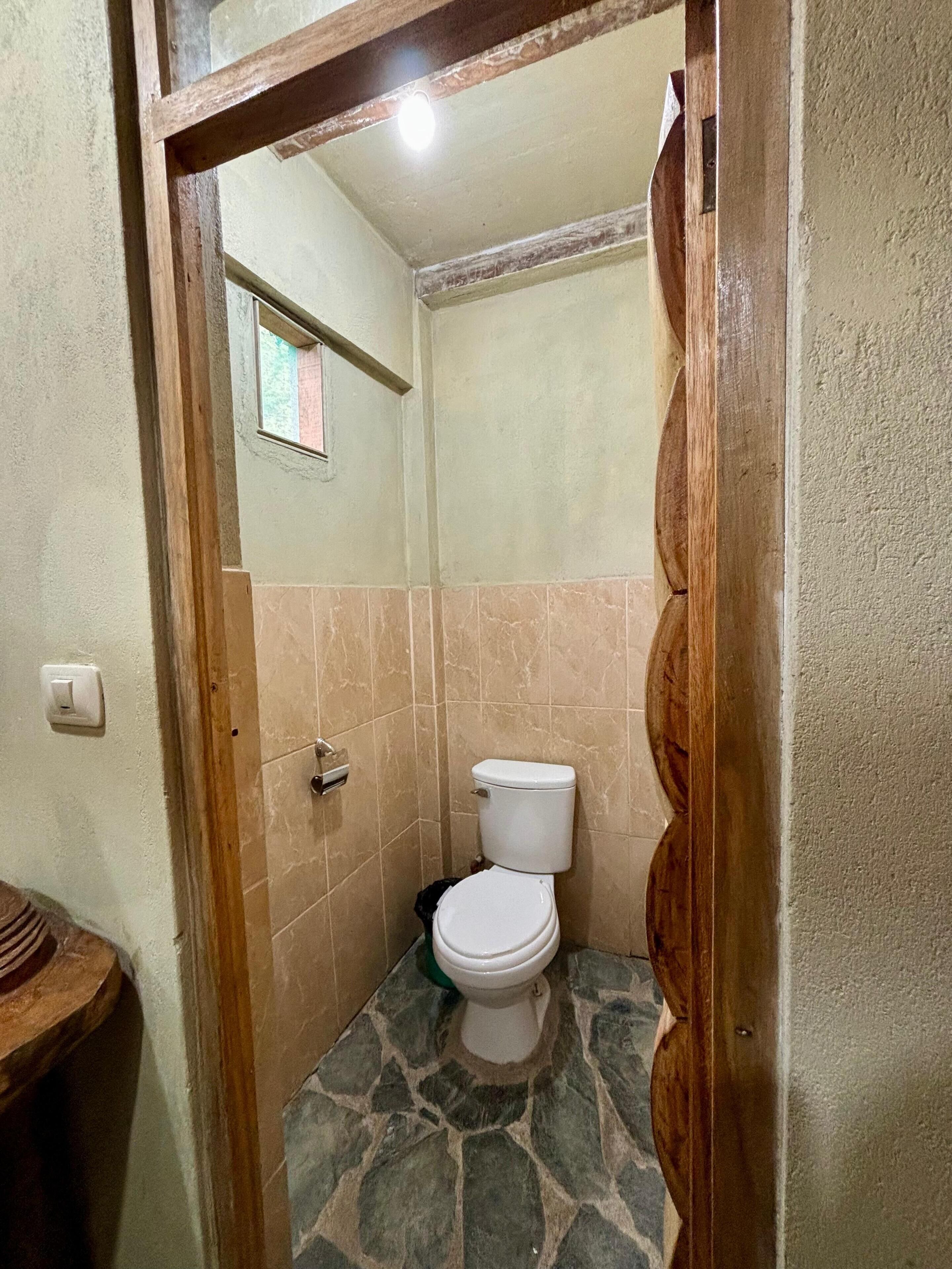 Un bagno piccolo con il water, una zona doccia e una porta con stipite in legno.