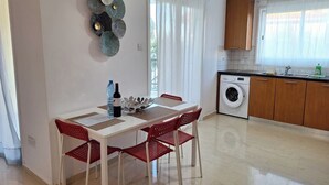 Eine kompakte Küche mit Waschmaschine, ein Essbereich mit Tisch und Stühlen sowie eine dekorative Wandgestaltung.