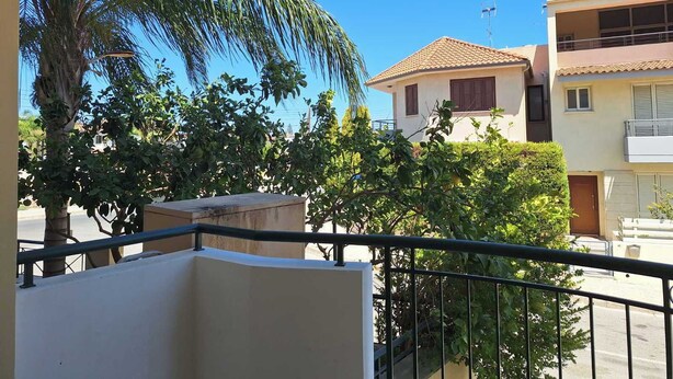 Ein Balkon mit Blick auf umliegende Gebäude und eine Palme.