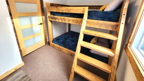 Una cama litera con escalera, una puerta con paneles de vidrio esmerilado y una ventana.