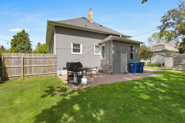 Une maison de plain-pied avec un patio, un barbecue et un abri de jardin.