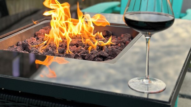 Ein Glastisch mit Feuerstelle und einem Glas Rotwein.