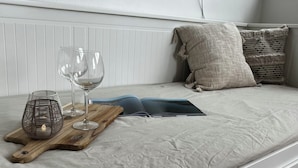 A neatly made bed with a grey bedspread, a wooden tray with a candle and wine glasses, and a book. - Apartment Emilio - Small apartment with great lake and alpine views (Überlingen)