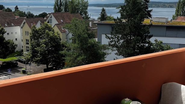 A balcony with a view of a lake, buildings, and trees. - Apartment Emilio - Small apartment with great lake and alpine views (Überlingen)