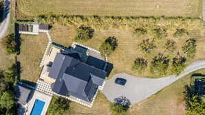 Luchtbeeld van een woonhuis met een groot huis, een zwembad en een oprit.