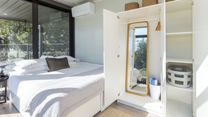 Een slaapkamer met een bed, een grote spiegel en een garderobe met manden.