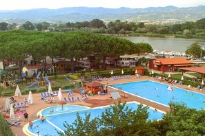 A swimming pool with a water slide, lounge chairs, and a view of a lake and mountains. - Cinque Terre Campsite Chalet 328 Near the sea (Ameglia)