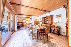Un comedor con una larga mesa de madera, sillas y una zona de cocina con armarios y estufa.