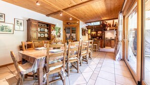 Een houten eetgedeelte met een tafel gedekt voor zes personen, houten stoelen en een kast met servies.