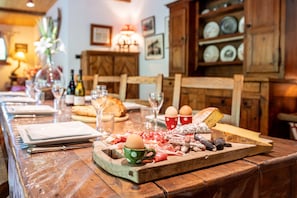 A wooden dining table with a charcuterie board, plates, and glasses.