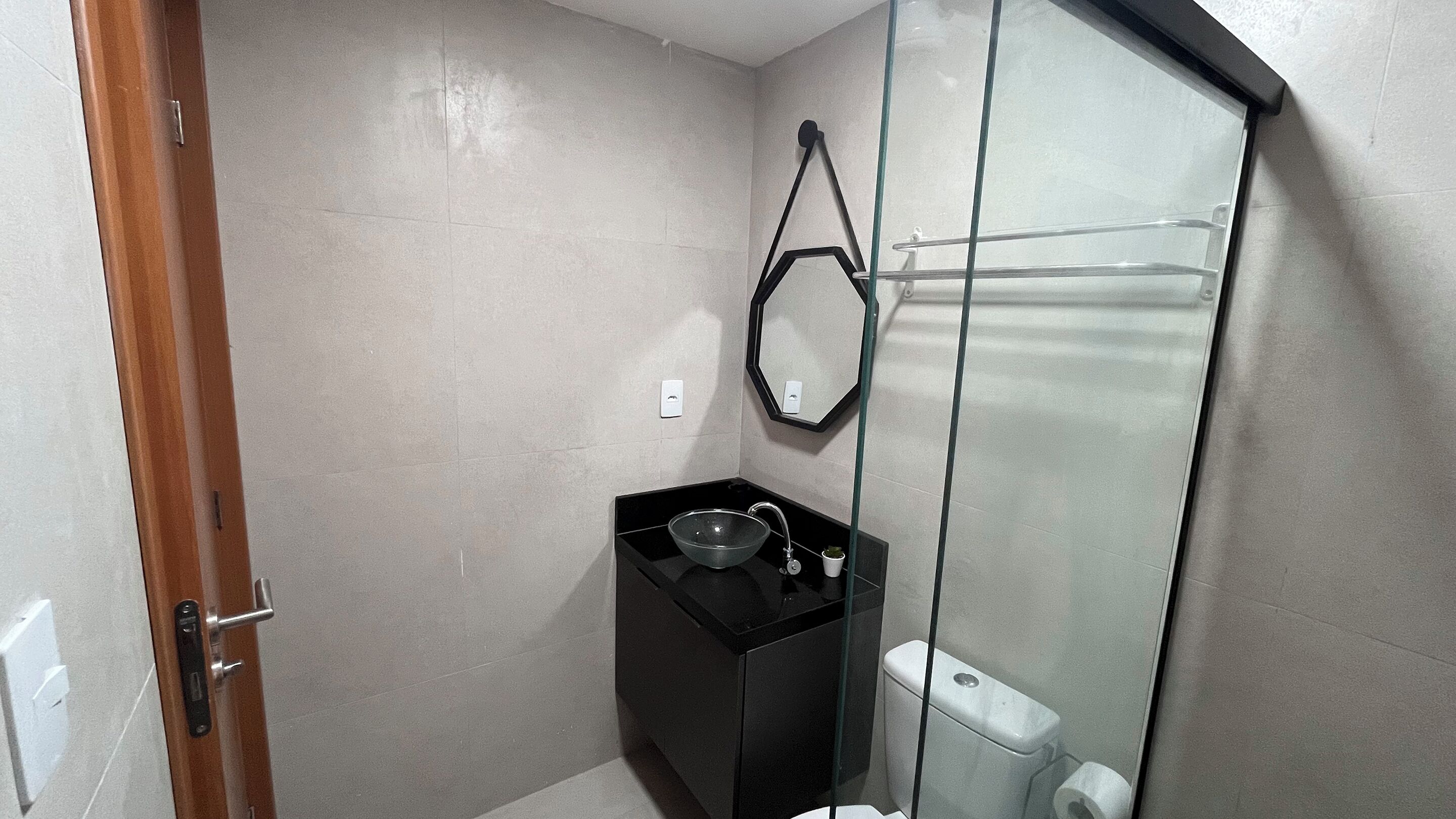 A bathroom with a glass shower enclosure, a black sink, and a toilet.