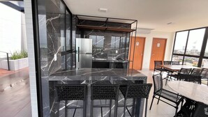 Een moderne keuken met een marmeren aanrechtblad, zwarte stoelen en een eethoek met een groot raam dat uitzicht biedt op de stad.