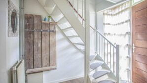 Een trap met houten treden en witte leuningen, een rustieke houten deur en een radiator aan de muur.