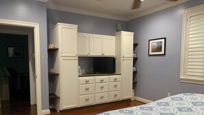 Un dormitorio con cama, televisión empotrada y armario.