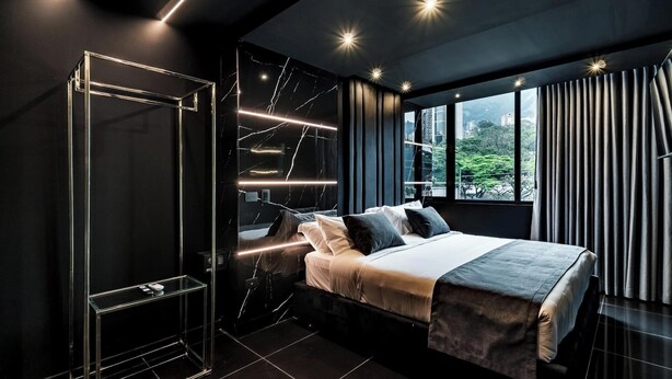 A modern bedroom with a bed, a glass cabinet, and a view of the outdoors through large windows. - 444 jds (Medellín)