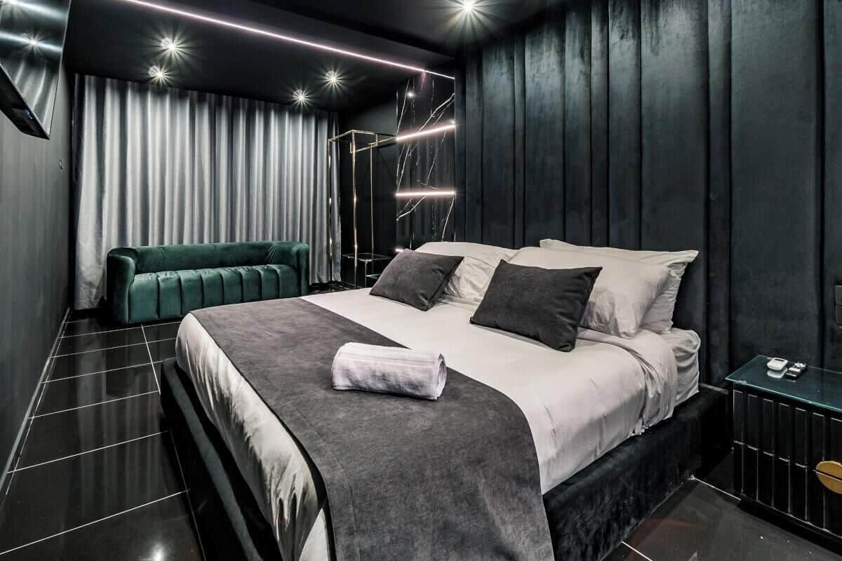 Un dormitorio moderno con una cama grande, un banco y una mesita de noche.