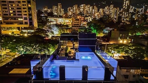 A rooftop terrace with a pool, surrounded by city buildings at night. - 444 jds (Medellín)