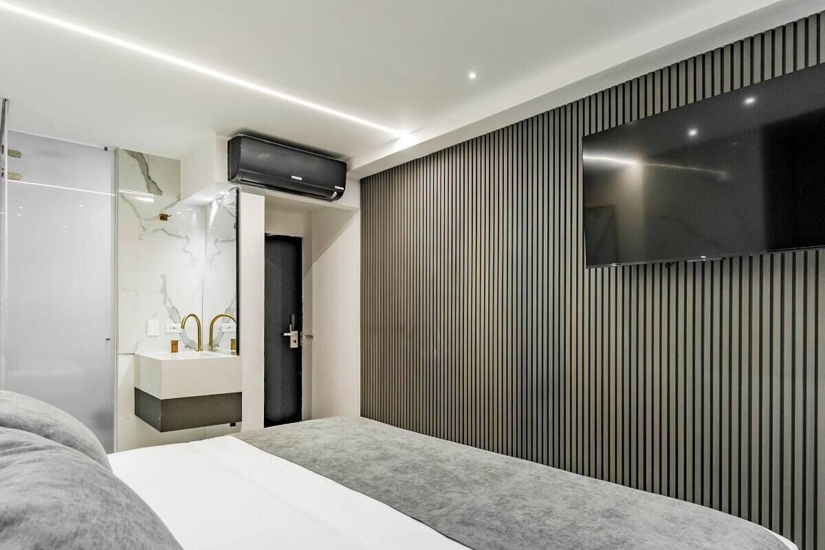 Un dormitorio moderno con una cama grande, un tocador empotrado con encimera de mármol y un televisor montado en la pared.