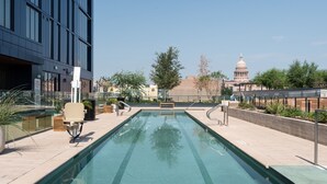 A swimming pool with lounge chairs and a view of a large building in the background. - Kasa at The Waller Austin (Austin)