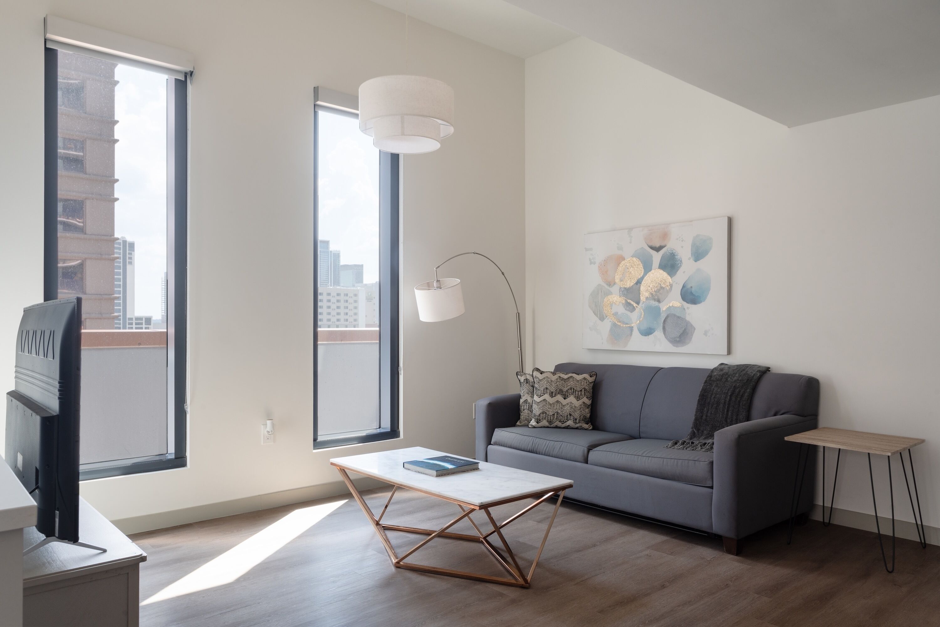 Ein modernes Wohnzimmer mit einer Couch, einem Couchtisch und einem Gemälde an der Wand.