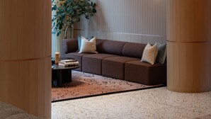 A modern interior with a brown sofa, a small table, and a potted plant. - Kasa at The Waller Austin (Austin)