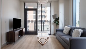 A modern living room with a flat-screen TV, a coffee table, a sofa, and a floor lamp. - Kasa at The Waller Austin (Austin)