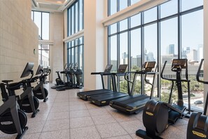 Une salle de sport équipée de tapis de course, de vélos d’appartement et d’appareils de musculation elliptique.