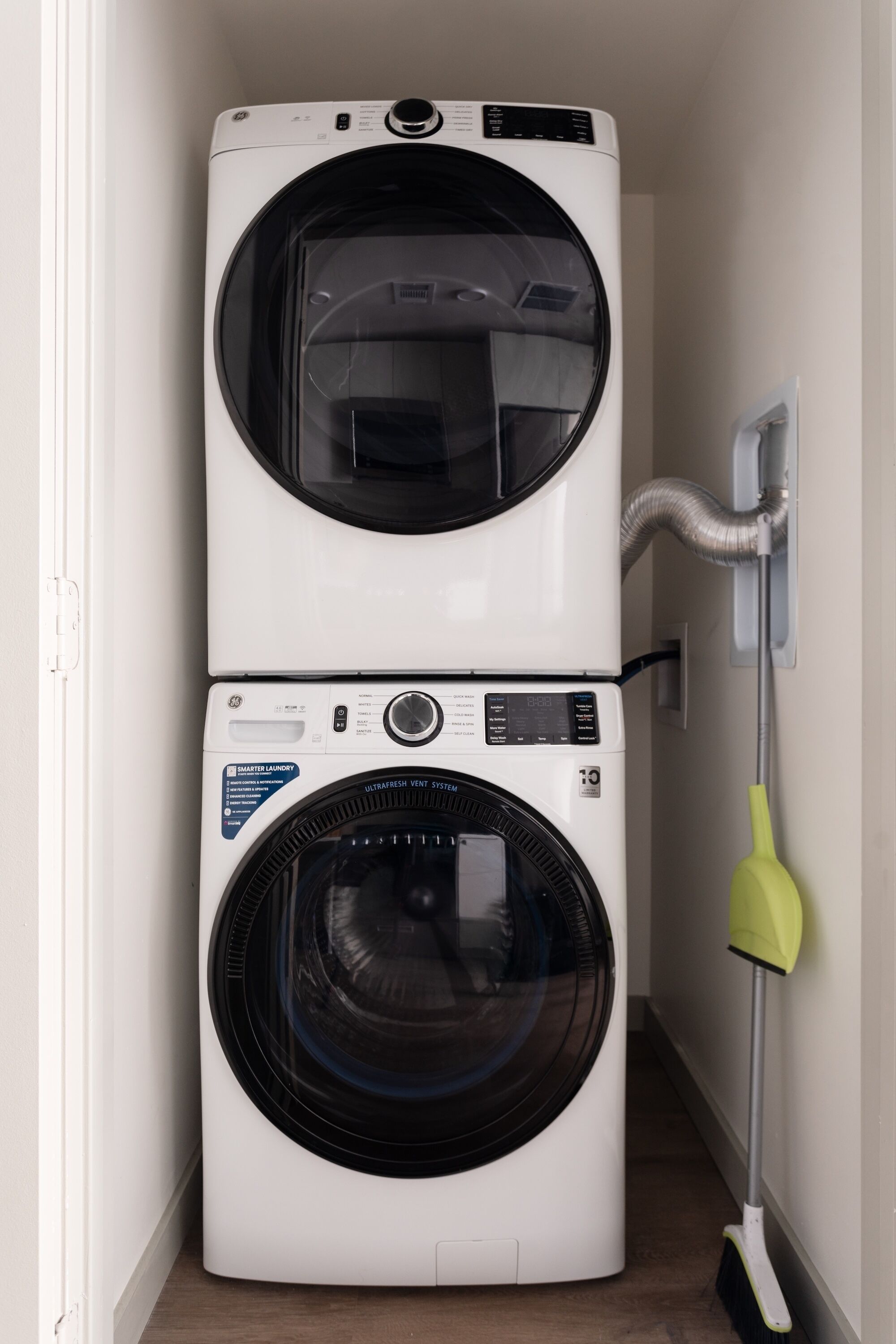 A stacked washer and dryer unit in a hallway.