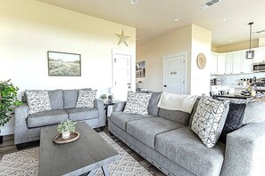 Una sala de estar con un sofá gris, una mesa de centro y una decoración con forma de estrella en la pared.