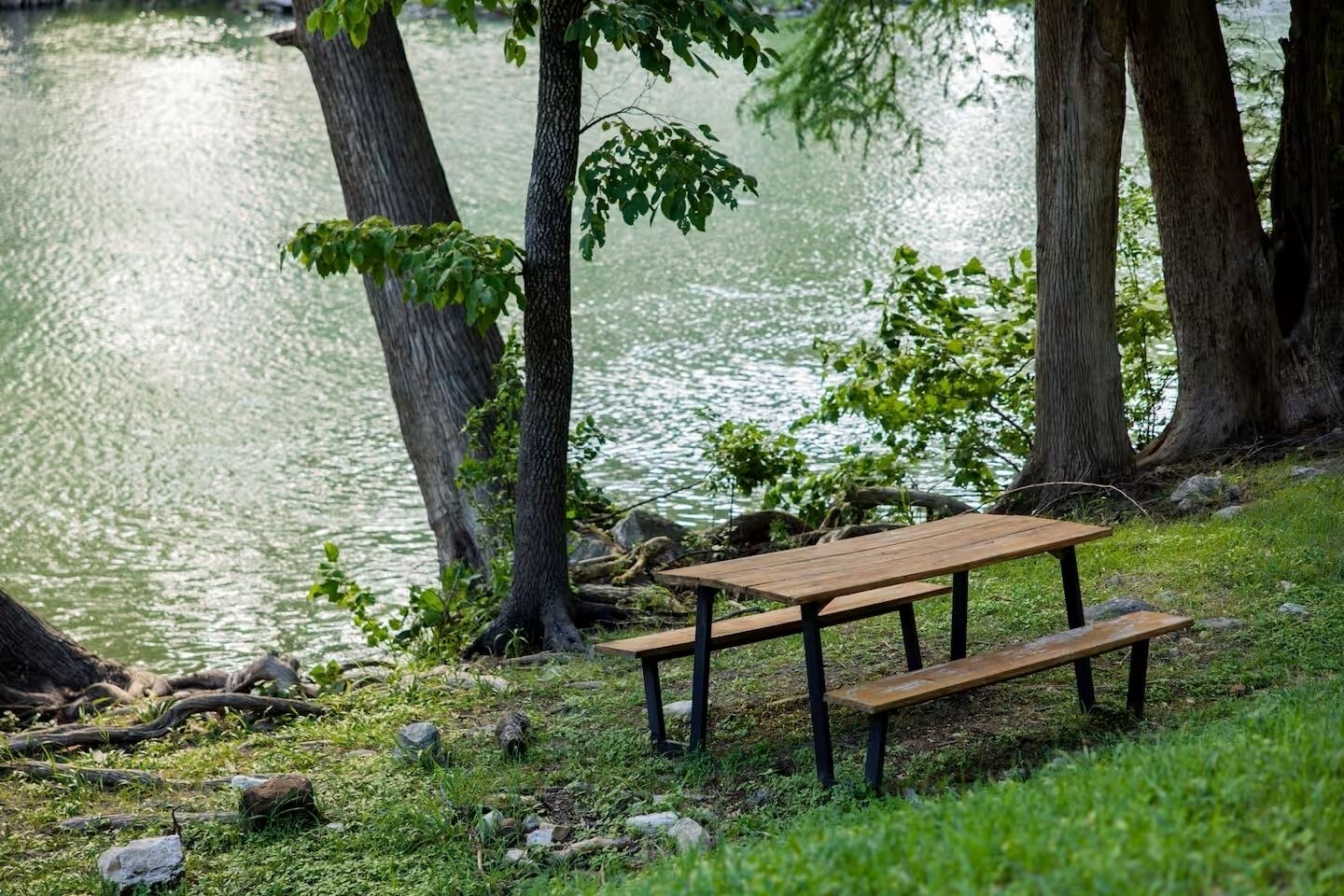 Una mesa de picnic junto a un lago rodeado de árboles.