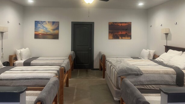 Une chambre d’hôtel avec deux lits simples, un ventilateur de plafond et des œuvres d’art accrochées aux murs.
