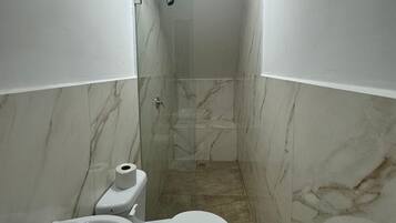 A narrow bathroom with a toilet, sink, and shower.