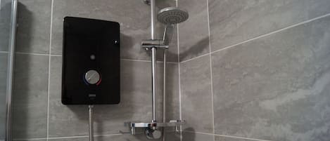 A modern bathroom with a built-in shower unit, a handheld showerhead, and a control panel.