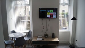A modern office space with a round table, two chairs, a desk with a computer monitor, and a floor lamp. - Bright & Stylish 1-bed Apt W/free Parking & Wi-fi (Dundee)